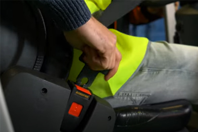 Alumno abrochando cinturón de la carretilla frontal